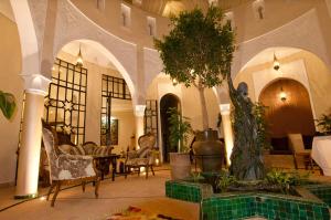 un vestíbulo con mesa, sillas y un árbol en La Claire Fontaine, en Marrakech