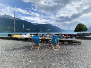 2 sillas y una mesa en una playa con un barco en Holiday Apartments Falke, en Brienz