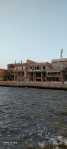 a building next to a body of water at شقق وشليهات رشيد علي ضفاف بحيره قارون in Shakshuk