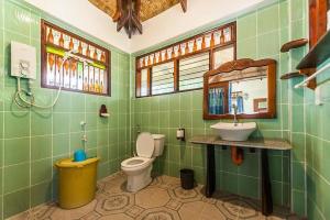a green bathroom with a toilet and a sink at Patrick's on the Beach Resort in General Luna