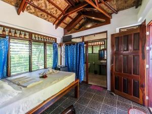 a bedroom with a bed with blue curtains and a television at Patrick's on the Beach Resort in General Luna