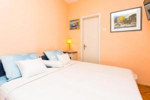 sypialnia z dużym białym łóżkiem z niebieskimi poduszkami w obiekcie Apartment Vukoja w Dubrowniku
