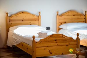 La Via Antiga في Cittànova: سريران خشبيان في غرفة نوم مع ملاءات ووسائد بيضاء