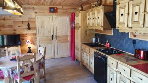 una cocina con armarios de madera y una mesa en una cabaña en Chez LAVALOU Gîte 4* chaleureux en bois, en Lannemezan