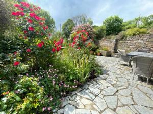 a garden with flowers and a table and a stone patio at May House A beautiful Cornish holiday home in the heart of Cornwall in Wadebridge