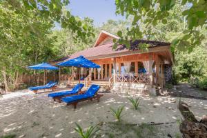 Siladen Resort & Spa في بوناكن: كابينة خشب بها كراسي ومظلات زرقاء