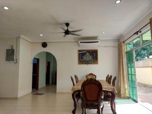 une salle à manger avec une table, des chaises et un ventilateur de plafond dans l'établissement AL' Indara Bunglow Homestay Taiping, à Taiping