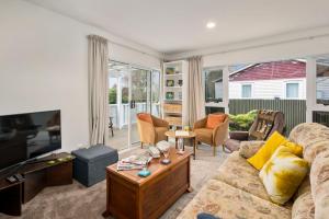 a living room with a couch and a tv at Plum Tree Cottage - Turangi Holiday Home in Turangi