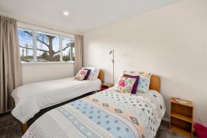 two beds in a room with a window at Plum Tree Cottage - Turangi Holiday Home in Turangi