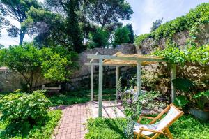 a garden with a wooden pergola and a chair at Apartments Eos & Vespera in Dubrovnik