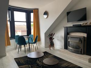 a living room with a fireplace and a table and chairs at Lovely 2 Bedroom Apartment in Central Location in Greenock
