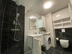 a bathroom with a shower and a sink and a washing machine at Apartment Vuky in Zagreb