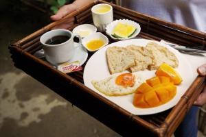 a tray with a plate of breakfast food with eggs and oranges at Fisheye The Rooms - Room 1 in El Nido