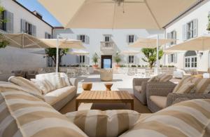 a patio with couches and tables and umbrellas at Heritage Hotel Kaštelet in Tučepi