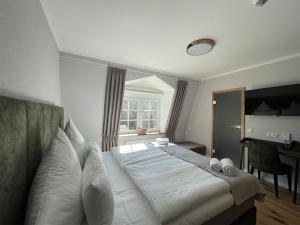 um quarto com uma cama com lençóis brancos e uma janela em Schlosshotel Brilon-Wald em Brilon-Wald