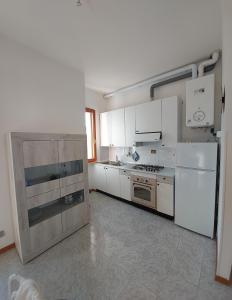 una cucina con armadietti bianchi, piano cottura e frigorifero di Appartamento Castiglioncello 600 mt dal mare a Castiglioncello