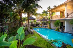 a villa with a swimming pool in front of a house at Asri Sari Villa Ubud in Ubud
