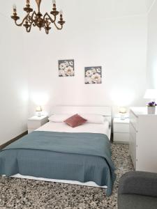 a white bedroom with a bed and a chair at Casa Lara in Castellammare del Golfo
