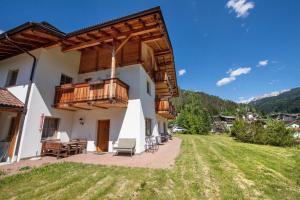 a house with a balcony and a yard at Apartments Berdan in Santa Cristina Gherdëina