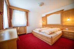 a bedroom with a bed and a window and red carpet at Apartments Berdan in Santa Cristina Gherdëina