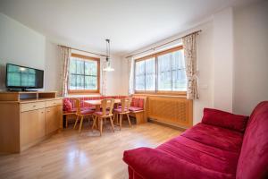 a living room with a red couch and a table at Apartments Berdan in Santa Cristina Gherdëina