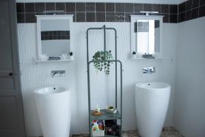 a bathroom with two white sinks and two mirrors at Maison Graciateguy in Saint-Étienne-de-Baïgorry