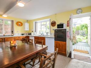 a kitchen with a wooden table and a kitchen with yellow walls at Arch Cottage in Lincoln