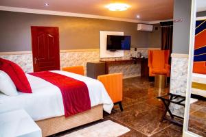 a bedroom with a bed with orange chairs and a television at Xilumani Hotel in Giyani