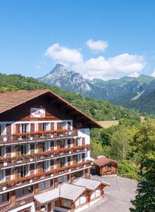 a hotel building with mountains in the background at Hotel Le Bois Joli in Bernex