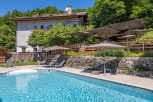 a swimming pool with chairs and umbrellas in front of a house at Hôtel Restaurant Le Bois Joli et SPA in Bernex