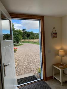 an open door with a view of a gravel road at Ploughmans Cottage in Forres