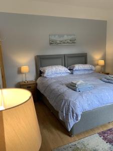 a bedroom with a bed with blue sheets and two lamps at Ploughmans Cottage in Forres