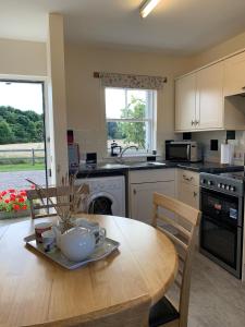 a kitchen with a wooden table and a dining room at Ploughmans Cottage in Forres