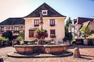 a building with a fountain in front of a house at Spacieux gîte jusqu'à 12 personnes in Ammerschwihr