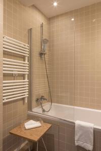 y baño con ducha y bañera con mesa. en Hôtel Arvor Saint Georges, en París 54 fotos más