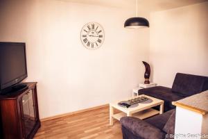 a living room with a couch and a clock on the wall at Spacieux gîte jusqu'à 12 personnes in Ammerschwihr
