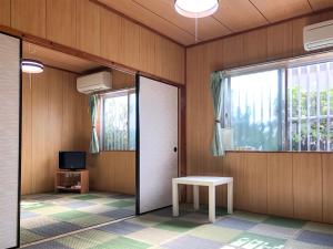 a room with a door and a table and a tv at Housei in Zamami