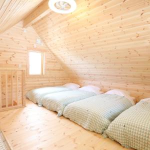 two beds in a room with a wooden ceiling at Log Cottage 白馬KIITOS in Hakuba
