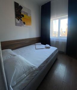 Cama blanca en habitación con ventana en LEOGRAND Apartments on Kniazia Romana 26, en Leópolis