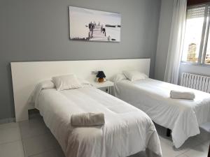 Cette chambre comprend 2 lits avec des draps blancs. dans l'établissement Hotel Venezuela, à Sanxenxo