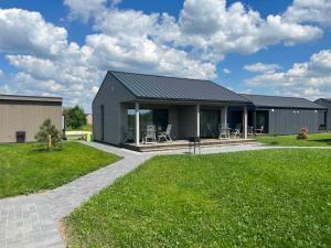 a gray house with a patio and grass at Apartamentai “Kuršių Snauda” in Palanga