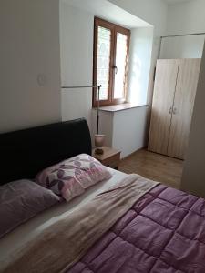 a bedroom with a bed with a purple comforter and a window at Valentino in Senj