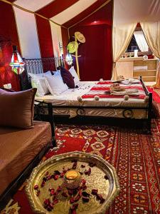a bedroom with two beds and a table in a room at Desert Heart Luxury Camp in Merzouga