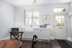 a kitchen with white cabinets and a table and chairs at The Pine Tree Cottage of Warren Lodge Boutique Cottages in Dromod