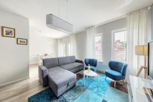 salon z kanapą i 2 niebieskimi krzesłami w obiekcie Shum Jeziora Apartament nr 7 w mieście Giżycko