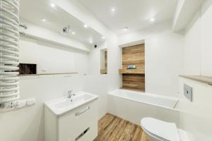 biała łazienka z umywalką i toaletą w obiekcie Shum Jeziora Apartament nr 7 w mieście Giżycko