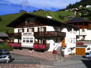 un gran edificio blanco con balcones y flores. en Garni Hotel Max, en Santa Cristina Valgardena