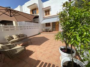 ベニカシムにあるCasa Ibicenca en Benicasim a 3 minutos de la playaのソファと椅子、木のあるパティオ