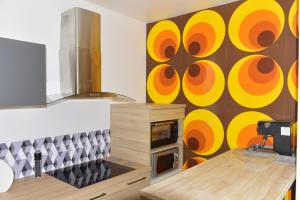 a kitchen with a wall with orange and yellow circles at Studio POP Canet En Roussillon in Canet-en-Roussillon +20 photos