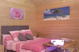 a bedroom with a pink bed with pillows and a table at Chalet l'emiline , Gite climatisé au sud d'aix avec piscine in Bouc-Bel-Air
